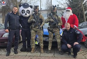 Na tle radiowozu: Mikołaj, maskotka policyjna, dwóch policjantów oraz dwóch kontterrorystów
