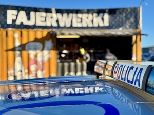 Dach radiowozu w tle stoisko z fajerwerkami