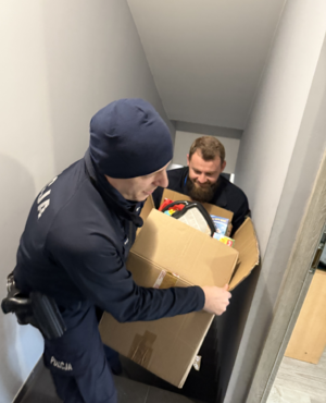 Dwaj policjanci wnoszący po schodach duży karton