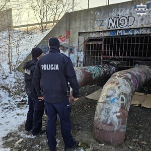 Dwaj policjanci przy przepuście ciepłowniczym w scenerii zimowej