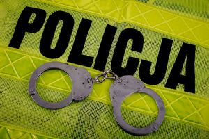 Policyjna kamizelka odblaskowa a na niej leżące srebrne kajdanki