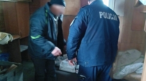 Wewnątrz pomieszczenia policjant oraz mężczyzna wyjmujący z torby różne produkty