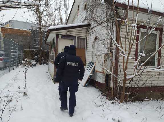 Dwaj policjanci idący do drewnianego budynku w scenerii zimowej