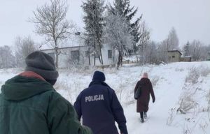 Kobieta, policjant i mężczyzna idący przez ośnieżone pole w kierunku zabudowań