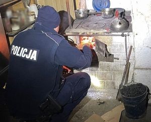 Policjant podkładający drwa do kaflowej kuchni