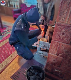 Policjant rozpalający piec kaflowy