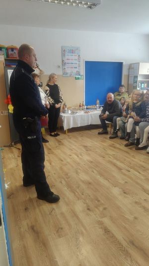 Policjant podczas pogadanki zgromadzonych seniorów i dzieci