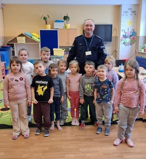 Policjant z grupką dzieci pozujący do zdjęcia w sali szkolnej
