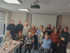 Grupa seniorów na świetlicy oraz dwaj policjanci