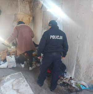 Zaśmiecony pustostan a wewnątrz bezdomny i policjant