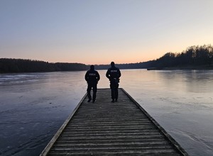 Dwaj policjanci na molo zbiornika wodnego w scenerii zimowej