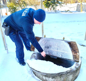 Policjant schylający się nad studnią