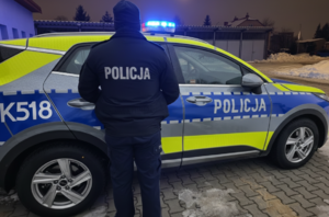 widziany z tyłu policjant na tle radiowozu