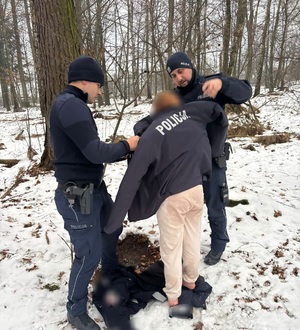 w scenerii zimowego lasu dwaj policjanci okrywający nastolatkę kurtką policyjną