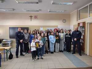 dwaj policjanci pozujący w sali szkolnej z grupą dzieci do zdjęcia