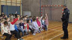 Policjant prowadzący pogadankę w sali gimnastycznej dla grupy dzieci