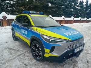 Radiowóz terenowy na tle ośnieżonego ogrodzenia posesji