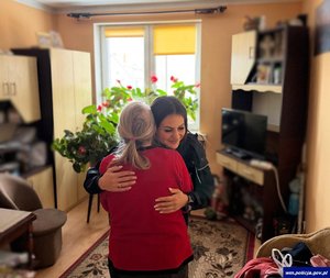 Wewnątrz mieszkania policjantka obejmująca staruszkę