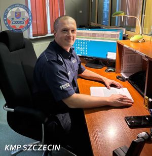 Policjant za biurkiem pozujący do zdjęcia