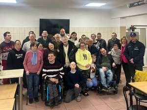 Grupa niepełnosprawnych pozująca w świetlicy do zdjęcia z policjantem