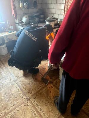 Policjant rozpalający ogień w kuchni kaflowej, obok staruszek