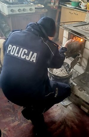 Policjant rozpalający ogień w wiejskiej kuchni
