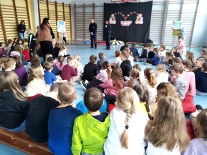 Dwójka policjantów prowadzących pogadankę w sali gimnastycznej pogadankę dla dzieci