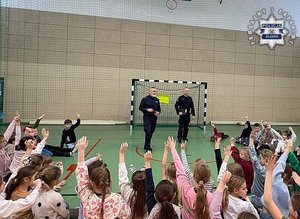 Dwóch policjantów podczas pogadanki dla dzieci w sali gimnastycznej