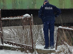 Widziany od tyłu w scenerii zimowej policjant nachylający się nad ogrodzeniem obok mostu