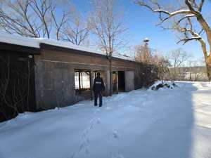 Policjant przy drewnianej wiacie gospodarczej w scenerii zimowej