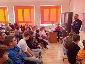 Policjant podczas pogadanki dla dzieci w sali szkolnej