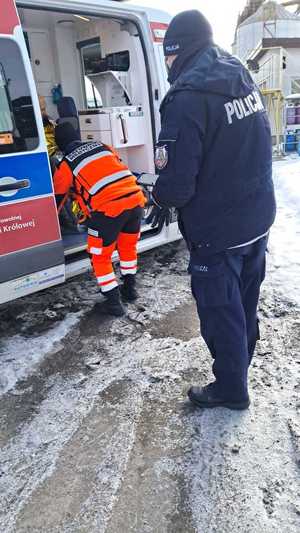 W scenerii zimowej policjant obok karetki i ratownika medycznego