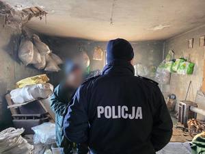 Widziany z tyłu policjant oraz mężczyzna w pustostanie