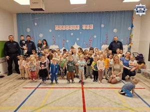 Trzej policjanci z grupką dzieci pozujący do zdjęcia wewnątrz sali