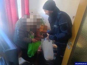 Policjant wręczający siatki z zakupami staruszce w mieszkaniu