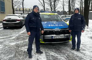 W scenerii zimowej dwaj policjanci obok radiowozu