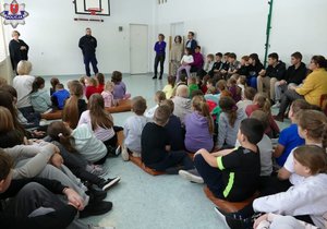 Policjant podczas prelekcji dla dzieci i młodzieży w sali gimnastycznej