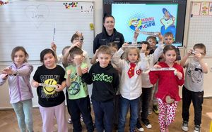 Policjantka z grupą dzieci pozująca do zdjęcia w sali przedszkolnej