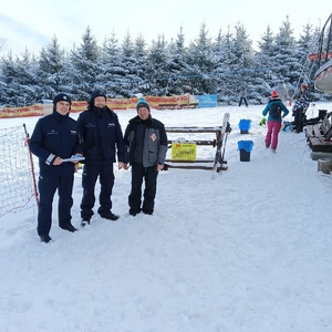 Na stoku pozujący do zdjęcia dwaj policjanci i mężczyzna w sportowej kurtce