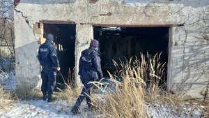 W scenerii zimowej dwaj policjanci zaglądający do ruiny budynku