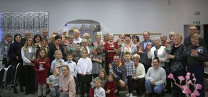 Wewnątrz sali grupa seniorów, dzieci pozująca z policjantką do zdjęcia