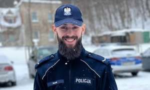 Uśmiechnięty policjant z brodą na tle ośnieżonego dziedzińca komisariatu