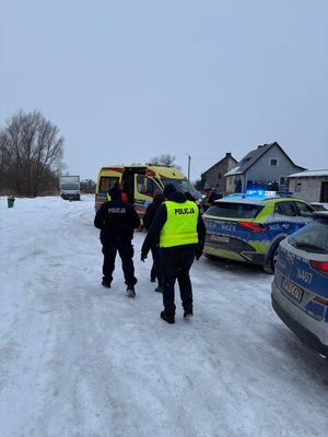 W scenerii zimowej policjanci obok karetki pogotowia i radiowozów