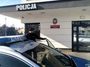 Policjant wsiadający do radiowozu przed posterunkiem Policji