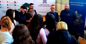 Grupa policjantów otoczona na sali przez młodzież