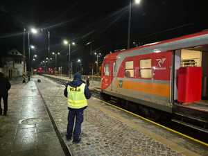 W scenerii nocnej policjant na peronie obok pociągu