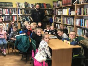 Uśmiechnięty policjant z dziećmi w bibliotece