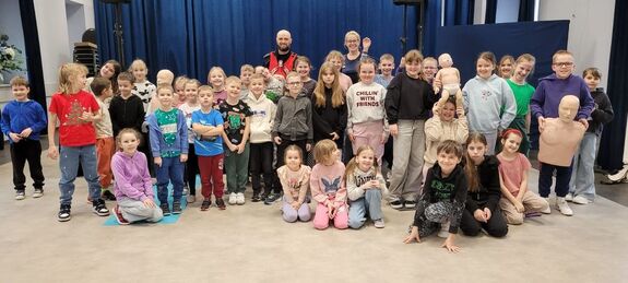 Grupa dzieci pozująca wewnątrz sali z policjantem do zdjęcia