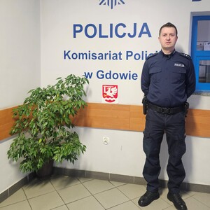 Policjant na tle baneru policji wewnątrz budynku