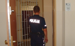 Policjant przed kratą aresztu